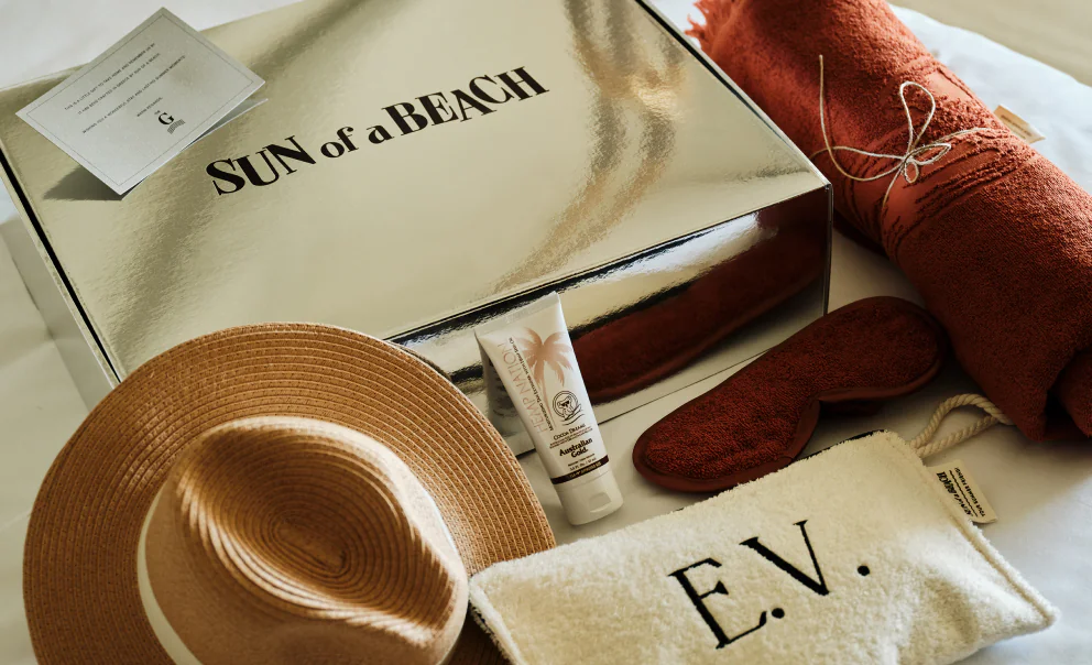 A Sun of a Beach welcome gift set, including a towel, hat, eye mask, and a small bag, offered as a complimentary gift by hotels.